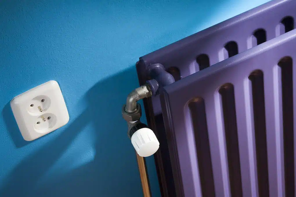 Paarse radiator tegen blauwe muur, ideaal voor energiezuinige verwarming en duurzaam wonen.